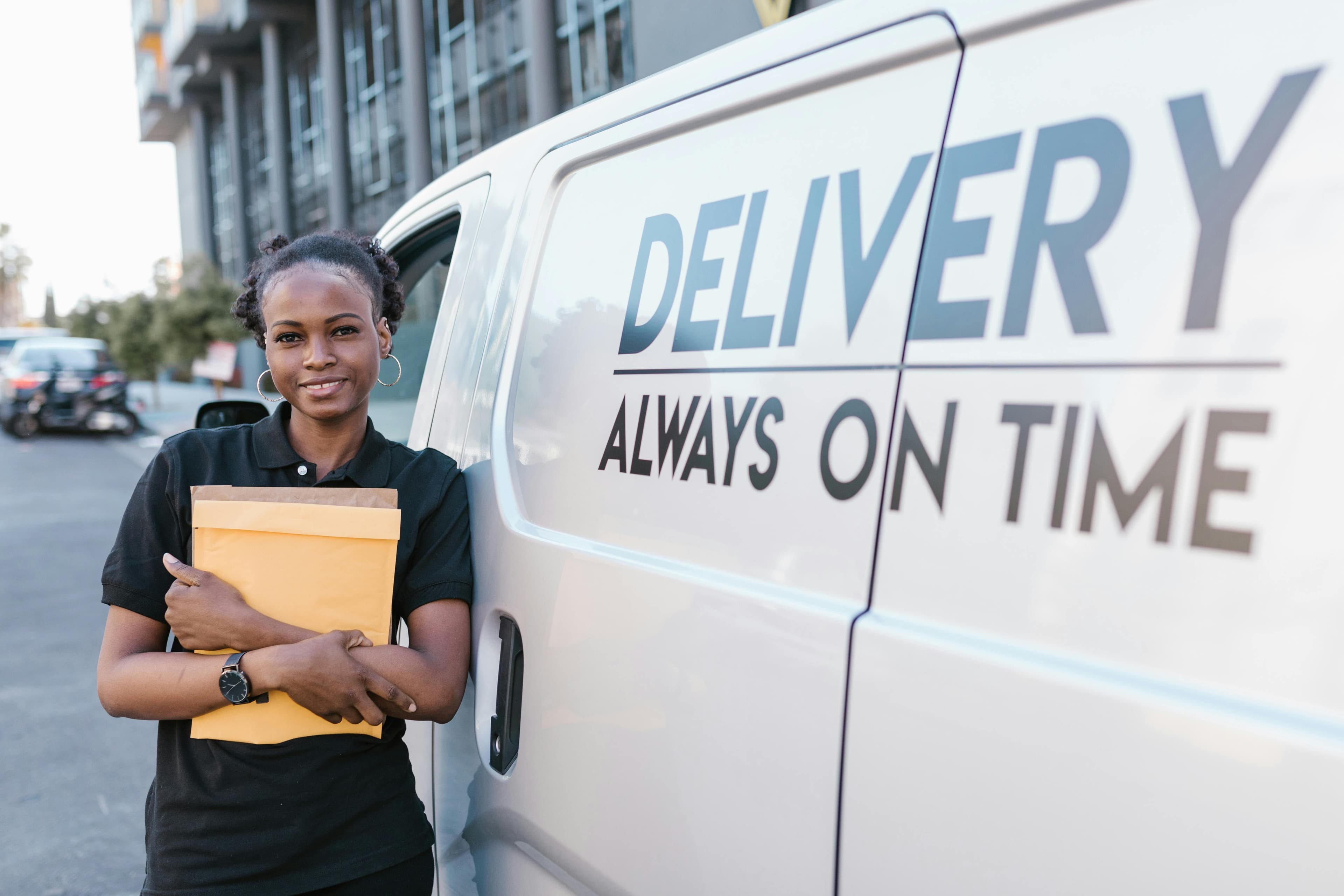 A courier with a parcel beside her van
